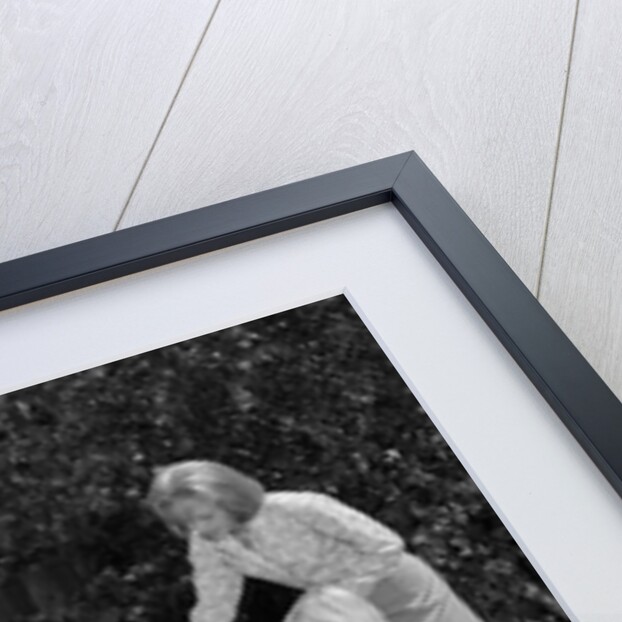 1960s man on patio grilling steak with 2 daughters seated at picnic table & wife standing serving food by Anonymous