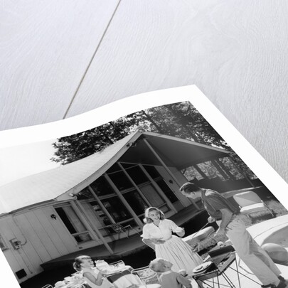 1950s family grilling hamburgers beside pool in backyard cookout by Anonymous