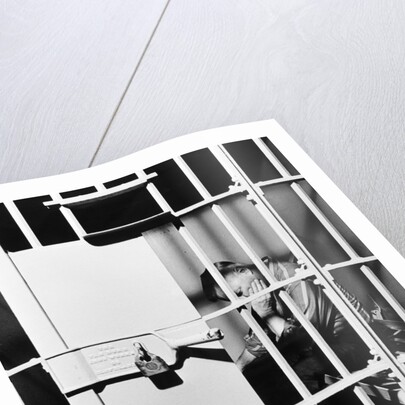 1960s man seated on bench in jail cell with head in hand looking downward by Anonymous