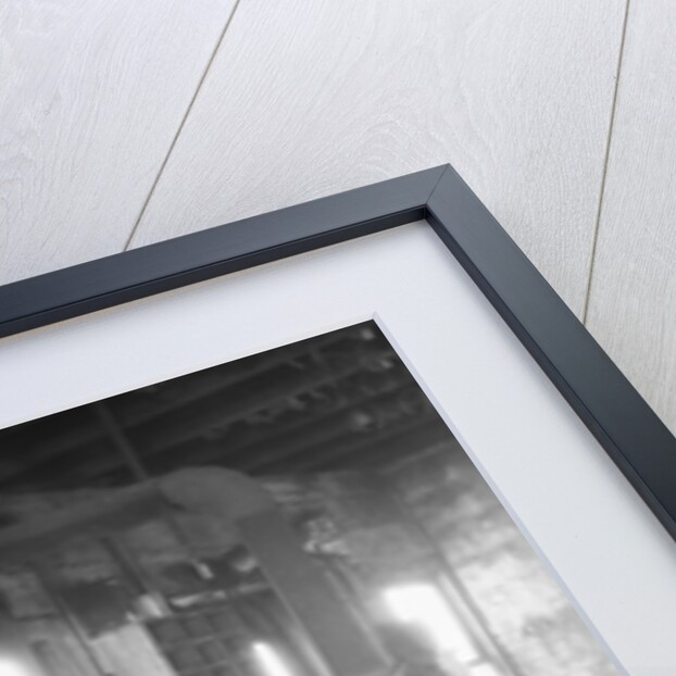 1930s elderly blacksmith with hammer at anvil as young boy holding harness looks on smiling by Anonymous