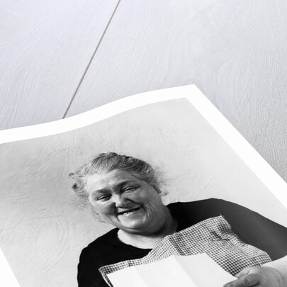 1930s 1940s elderly character woman smiling reading letter wearing apron looking at camera by Anonymous