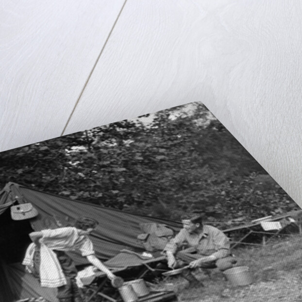 1920s couple man woman on fishing camping trip vacation at campsite man cooking over fire by Anonymous