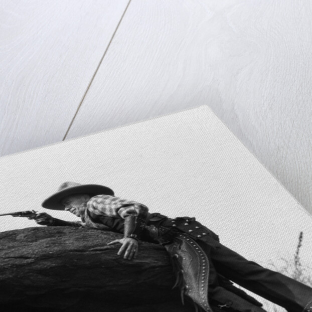 1920s cowboy among rocks aiming revolver by Anonymous