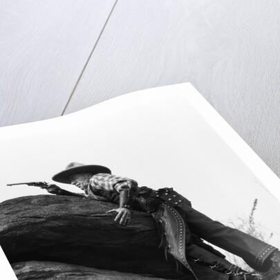 1920s cowboy among rocks aiming revolver by Anonymous