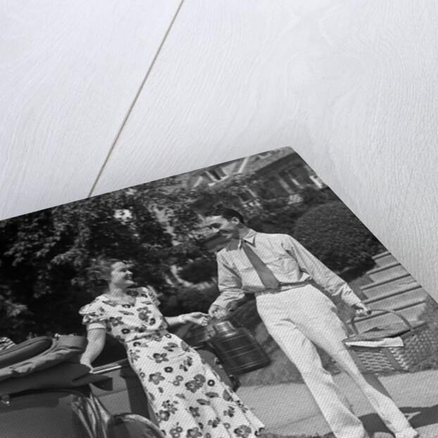1930s family of four getting into convertible automobile with picnic basket and thermos jug by Anonymous