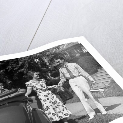 1930s family of four getting into convertible automobile with picnic basket and thermos jug by Anonymous