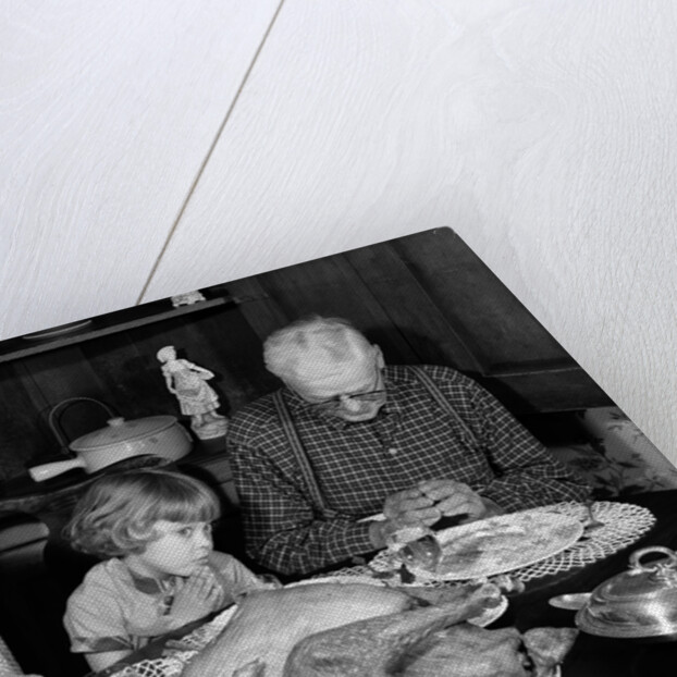 1950s 1960s little girl look at turkey sitting between grandmother grandfather saying grace at table by Anonymous