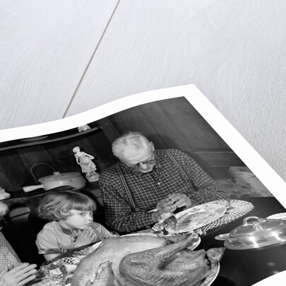 1950s 1960s little girl look at turkey sitting between grandmother grandfather saying grace at table by Anonymous