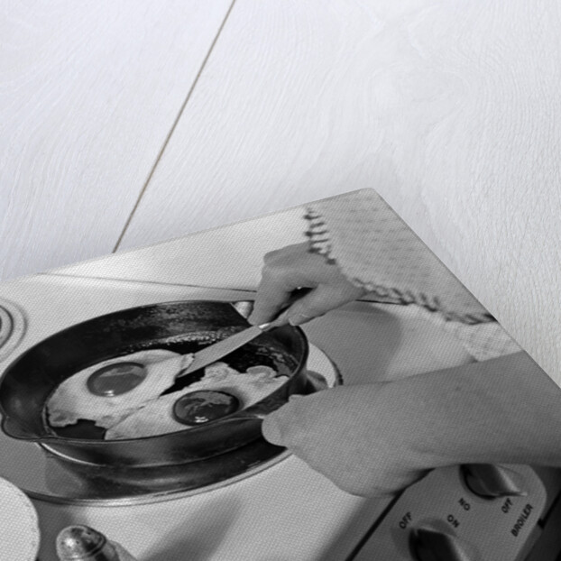 1940s 1950s woman hands frying eggs in iron skillet on electric stove salt and pepper shakers by Anonymous