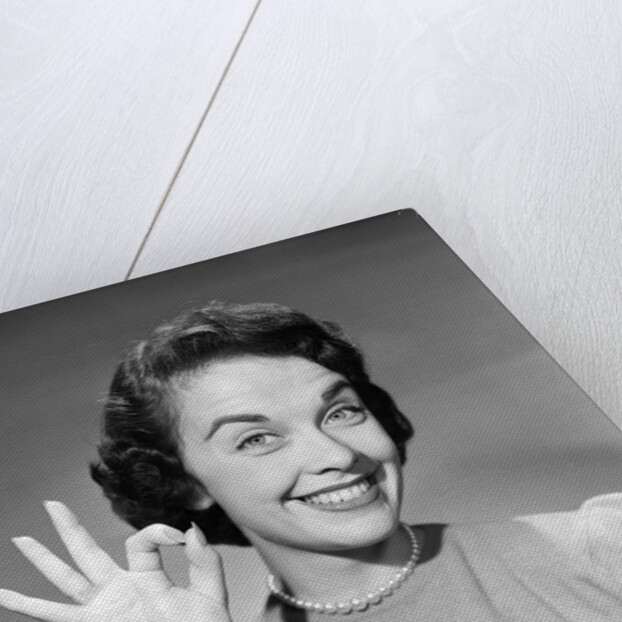 1950s woman smiling wearing pearl necklace looking at camera making okay gesture with hand by Anonymous