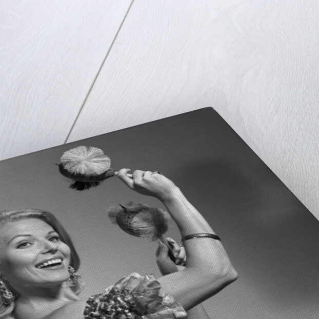 1960s smiling blond woman looking at camera shaking noise makers in her hands wear ruffled halter top by Anonymous