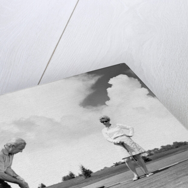 1960s older couple on golfing green man putting by Anonymous