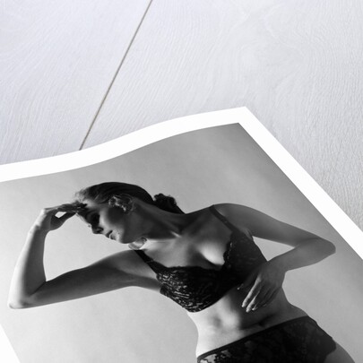 1970s woman wearing black lace bra and panties head turned to side hand touching forehead arms in graceful pose indoor by Anonymous