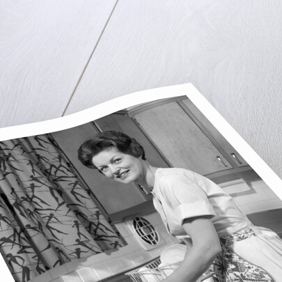 1960s woman housewife washing dishes in kitchen sink looking at camera by Anonymous
