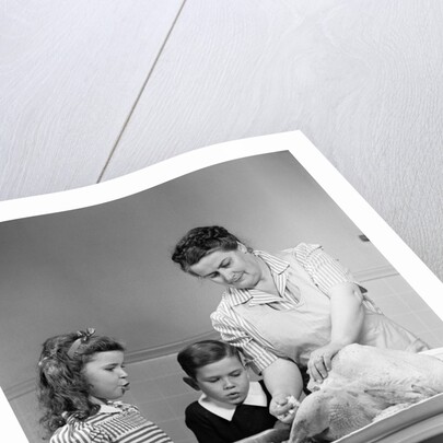 1940s mother son daughter in kitchen stuffing turkey for thanksgiving dinner by Anonymous
