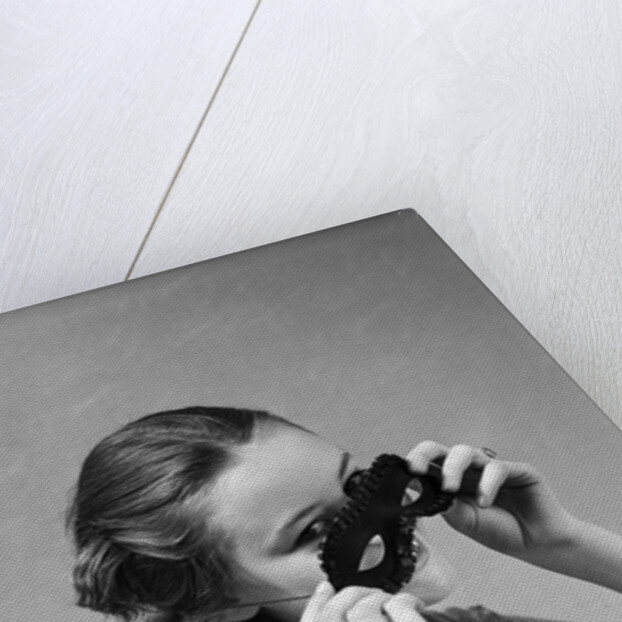 1930s 1940s woman putting on taking off black eye mask by Anonymous