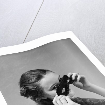 1930s 1940s woman putting on taking off black eye mask by Anonymous