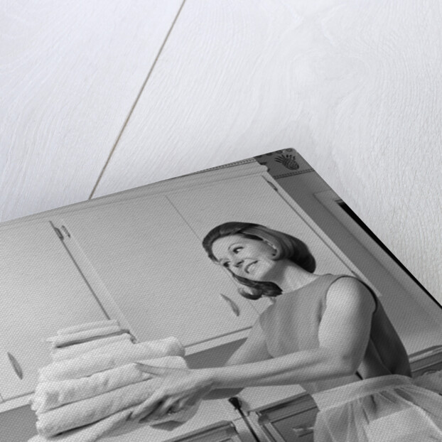 1960s satisfied woman homemaker holding folded laundry by Anonymous