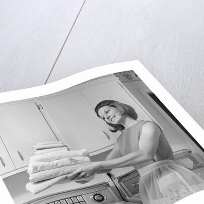 1960s satisfied woman homemaker holding folded laundry by Anonymous