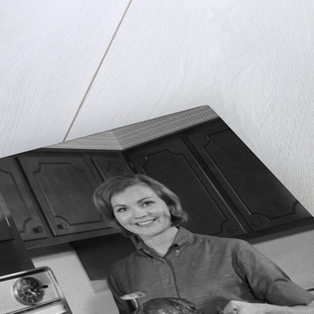 1960s smiling woman in kitchen taking roast out of oven looking at camera by Anonymous