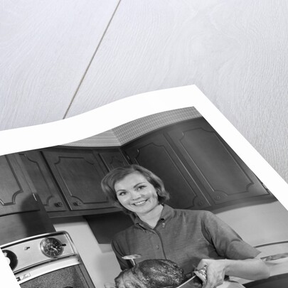 1960s smiling woman in kitchen taking roast out of oven looking at camera by Anonymous