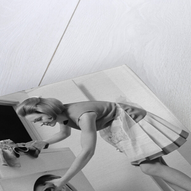 1970s woman removing laundry from dryer by Anonymous