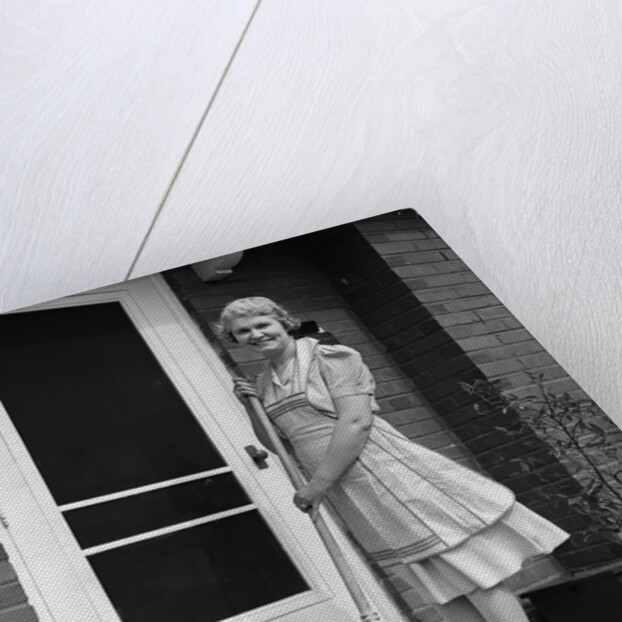 1940s smiling woman sweeping porch front door step with a broom looking at camera by Anonymous