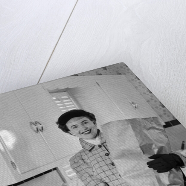 1950s smiling woman in kitchen holding grocery bag handbag wearing hat gloves looking at camera by Anonymous