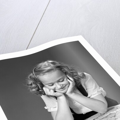 1940s child reading newspaper comics smiling by Anonymous