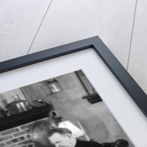 1930s family of four sitting in front fireplace mother knitting father reading smoking pipe kids doing homework by Anonymous