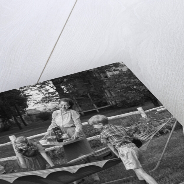 1950s mom & kids serving dad in hammock by Anonymous