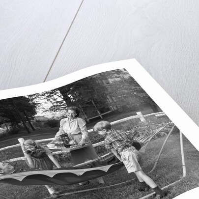 1950s mom & kids serving dad in hammock by Anonymous