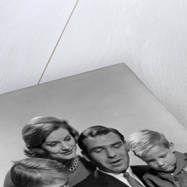 1960s family father mother sons reading book together by Anonymous