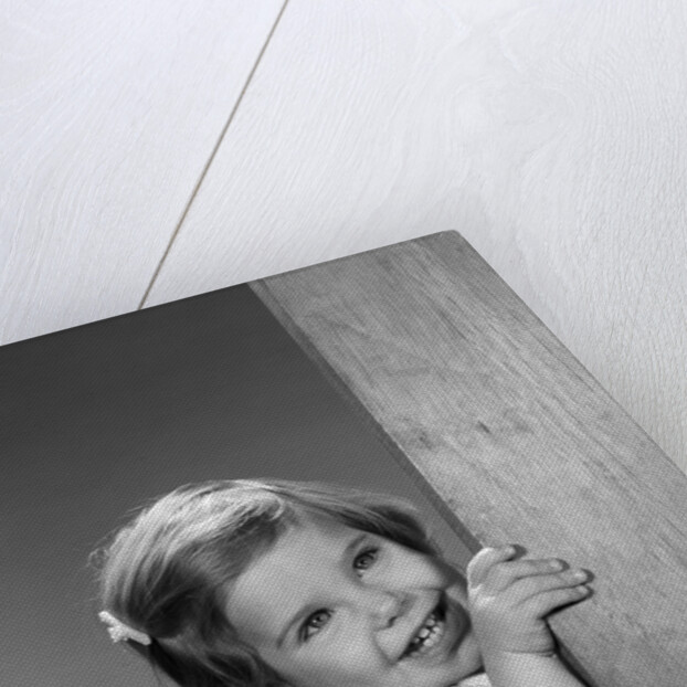 1960s child little girl smiling peeking around corner by Anonymous