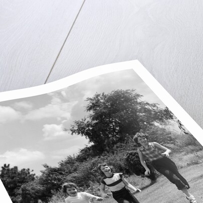 1950s three girls running in grassy field by Anonymous