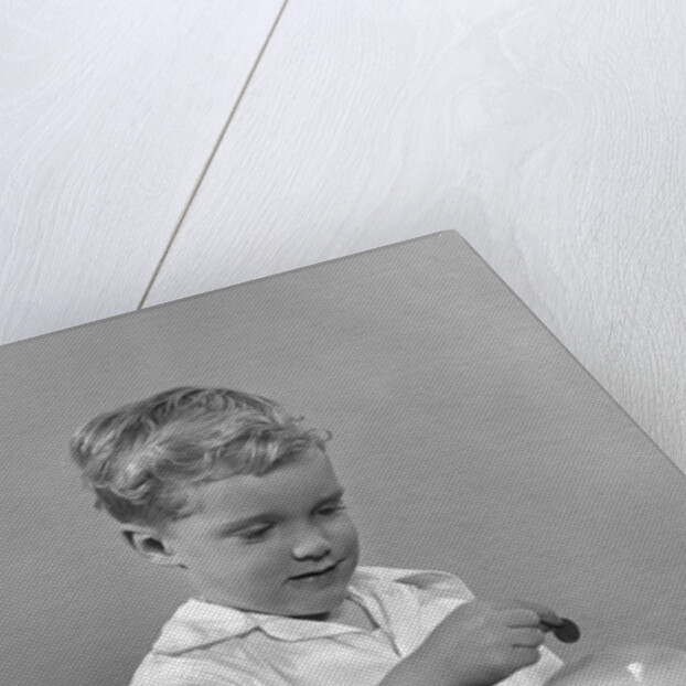 1950slittle boy putting coin into piggy bank by Anonymous