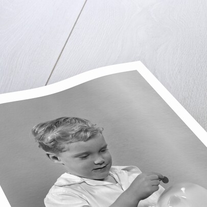 1950slittle boy putting coin into piggy bank by Anonymous