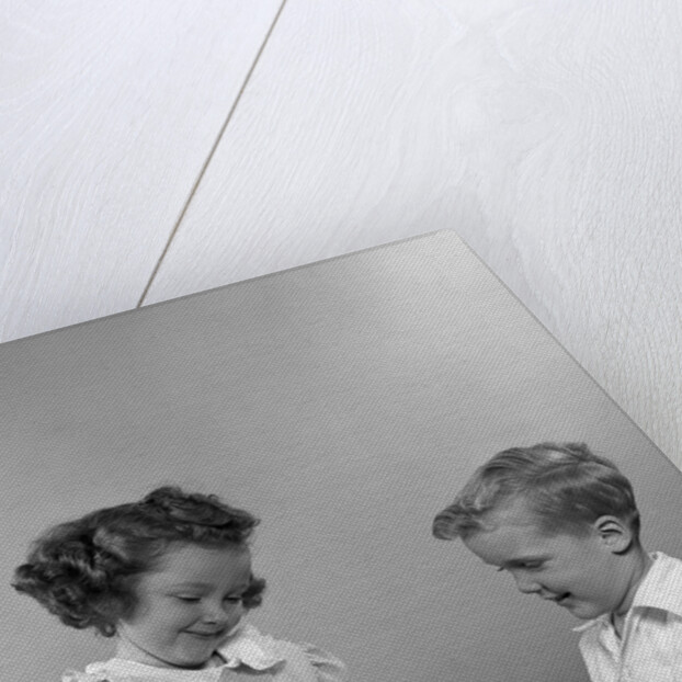 1950s little girl and boy putting coin into piggy bank by Anonymous