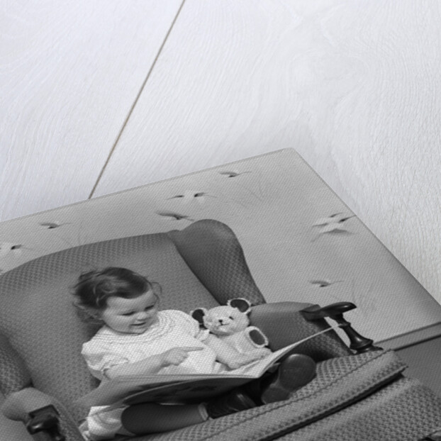 1930s little girl child in large chair with bear reading book by Anonymous