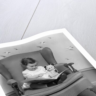 1930s little girl child in large chair with bear reading book by Anonymous