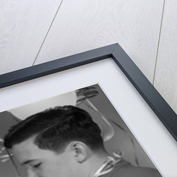 1960s teenage girl blowing out candles on birthday cake held by boy by Anonymous