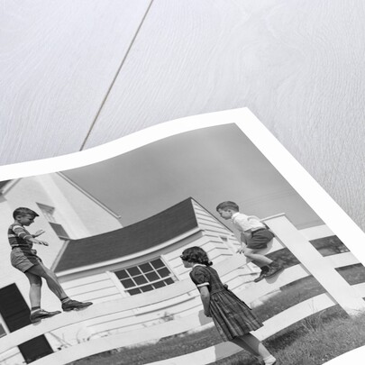 1950s boy walking balancing on fence other children standing sitting next to fence by Anonymous