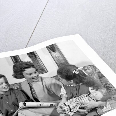 1960s mother sitting on couch with son and daughter by Anonymous