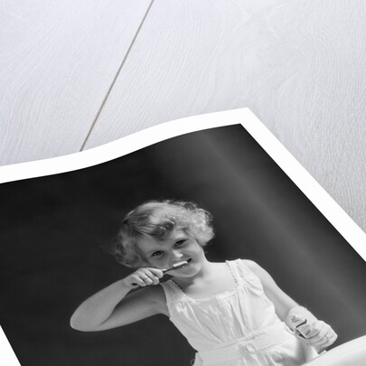 1930s child curly hair blond girl brushing teeth toothbrush looking at camera by Anonymous