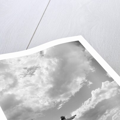 1950s 1960s family of four silhouetted on top rocky hill pointing at clouds in sky by Anonymous