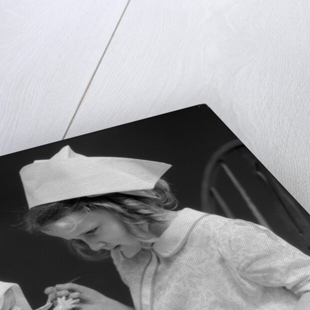 1930s little girl playing nurse with doll spoonful of medicine by Anonymous