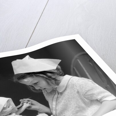 1930s little girl playing nurse with doll spoonful of medicine by Anonymous