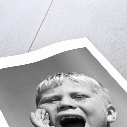 1950s blond boy with eyes closed and hand cupping a wide open mouth shouting by Anonymous