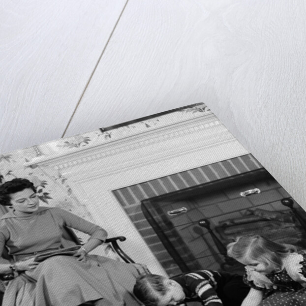 1950s mother watching son daughter playing game in front of fireplace by Anonymous