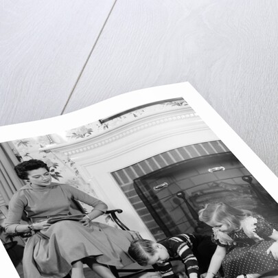 1950s mother watching son daughter playing game in front of fireplace by Anonymous